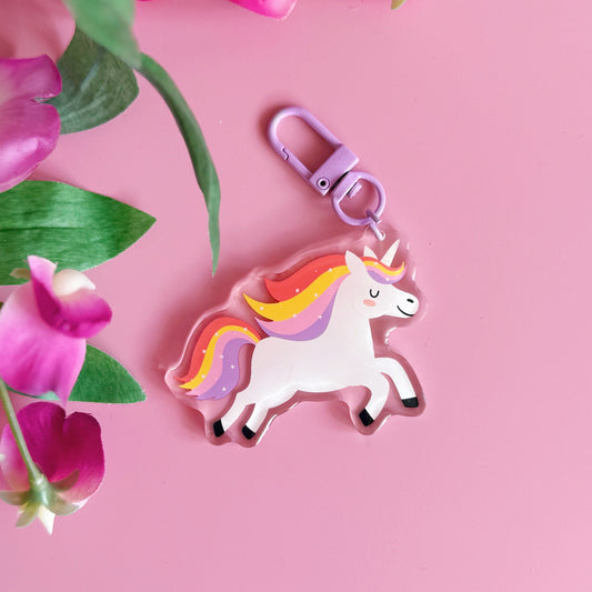 Unicorn keychain with colorful mane on a pink background with flowers