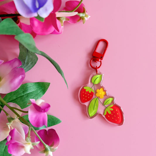 Strawberry-themed keychain with colorful flowers on a pink background