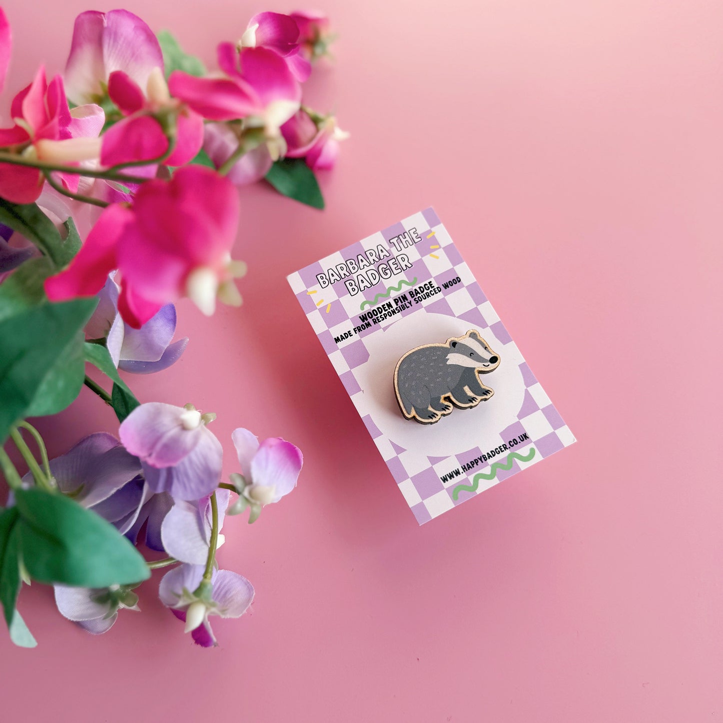 A wooden pin badge with a glossy finish, featuring an illustration of a badger.