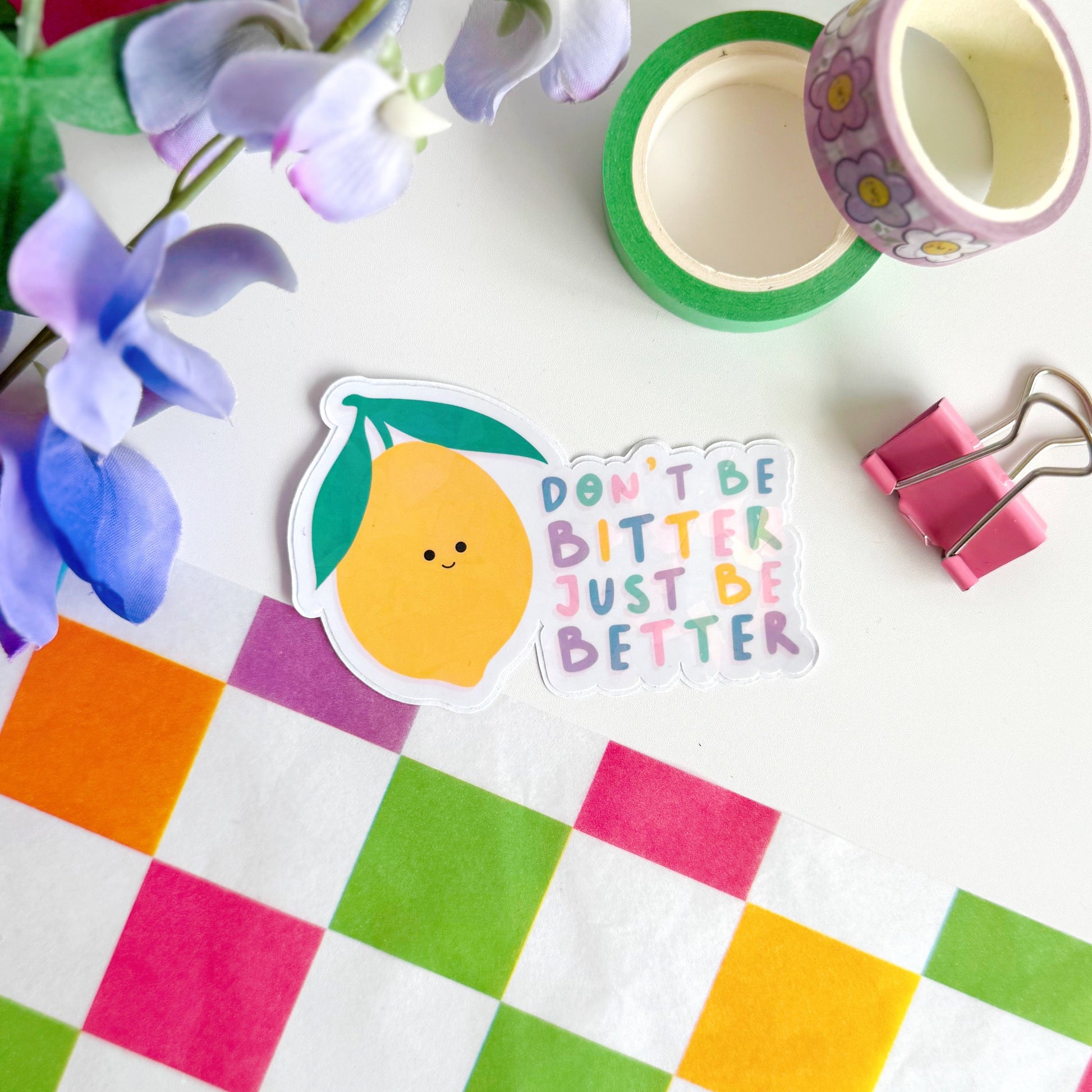 A holographic sticker, of a smiling lemon and the quote don't be bitter just be better. The sticker has an easy peel lip.