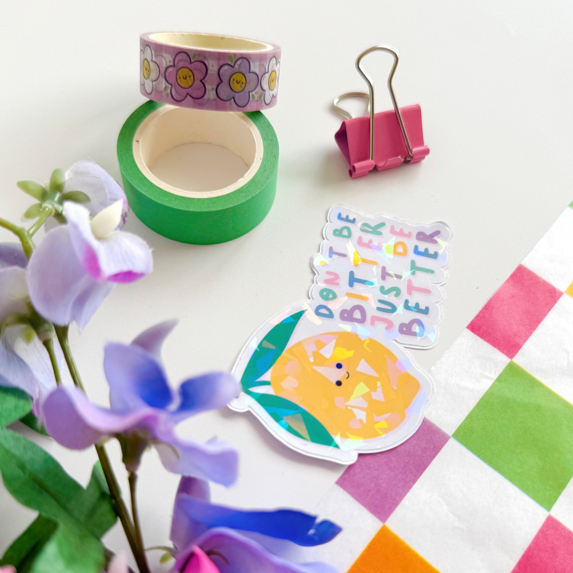 A holographic sticker, of a smiling lemon and the quote don't be bitter just be better. The sticker has an easy peel lip.