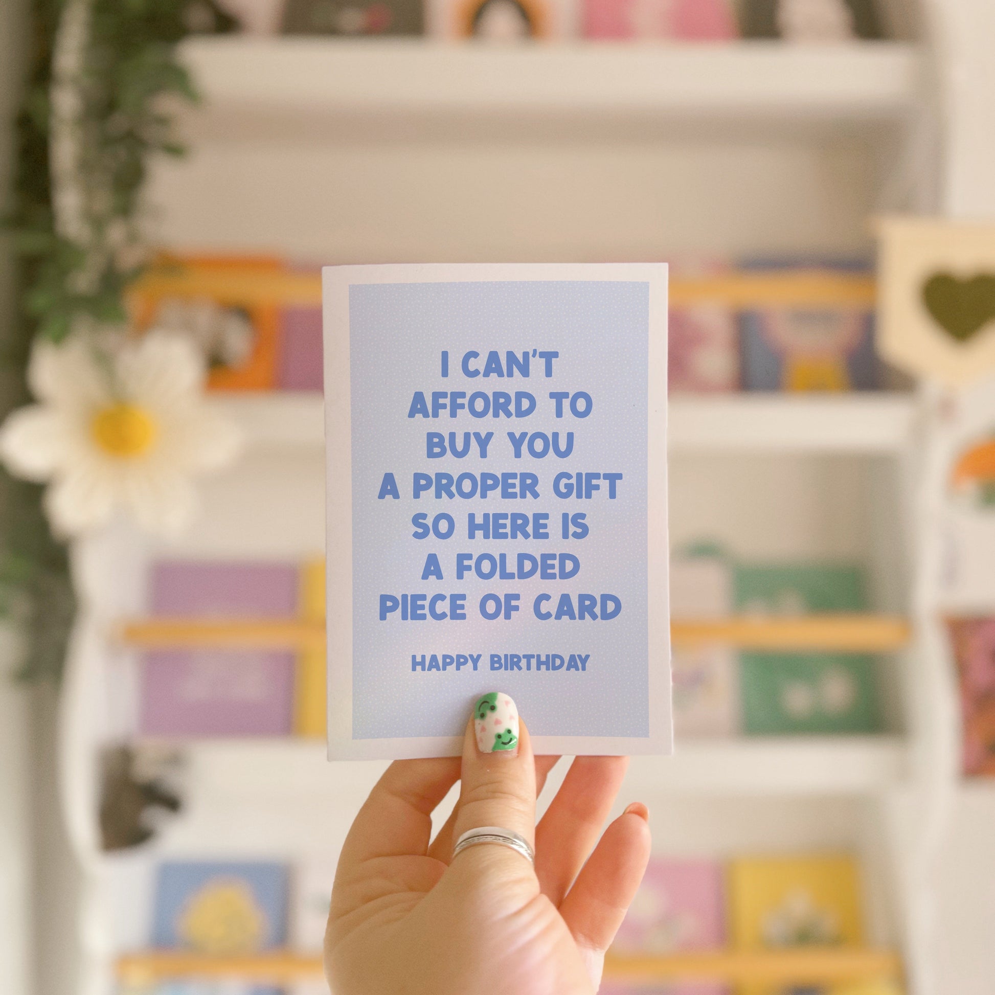 A blue card with red text, saying I can't afford to buy you a proper gift so here is a folded piece of card - happy birthday.