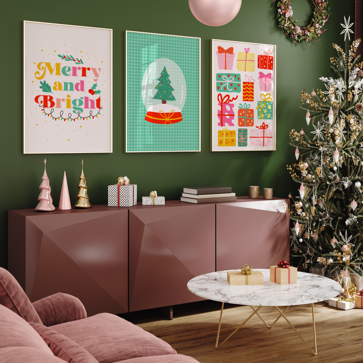 Three illustrated Christmas prints sit on a green wall next to a Christmas tree and various bits of festive decor.