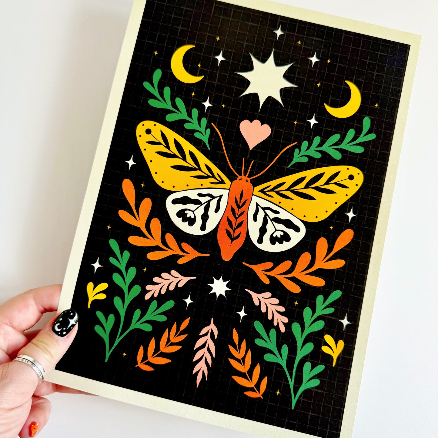 Colorful butterfly illustration on a black background held by a hand.
