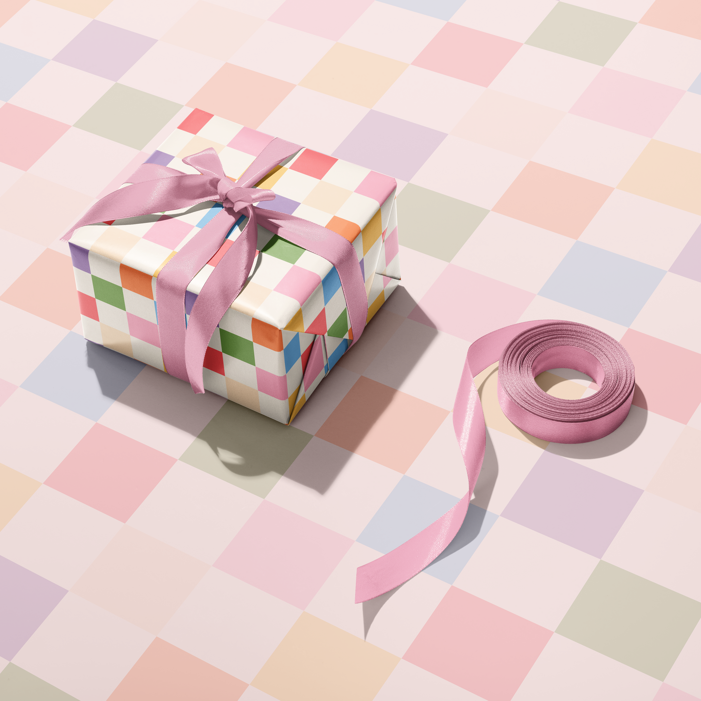 A multicoloured checkerboard pattern gift wrap, shown wrapped around a gift with blue ribbon.