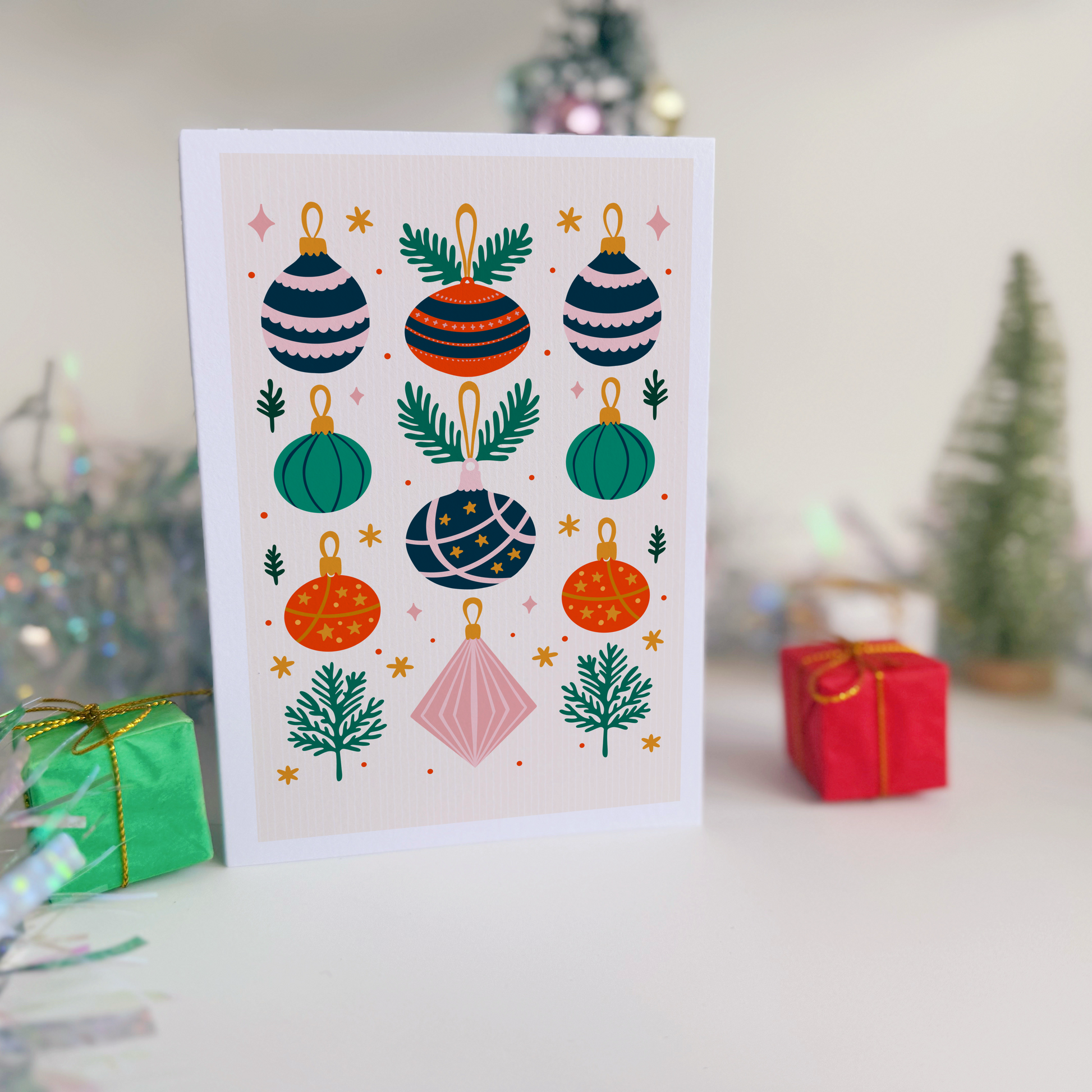 Christmas card with colorful ornaments on a white background, surrounded by festive decorations.