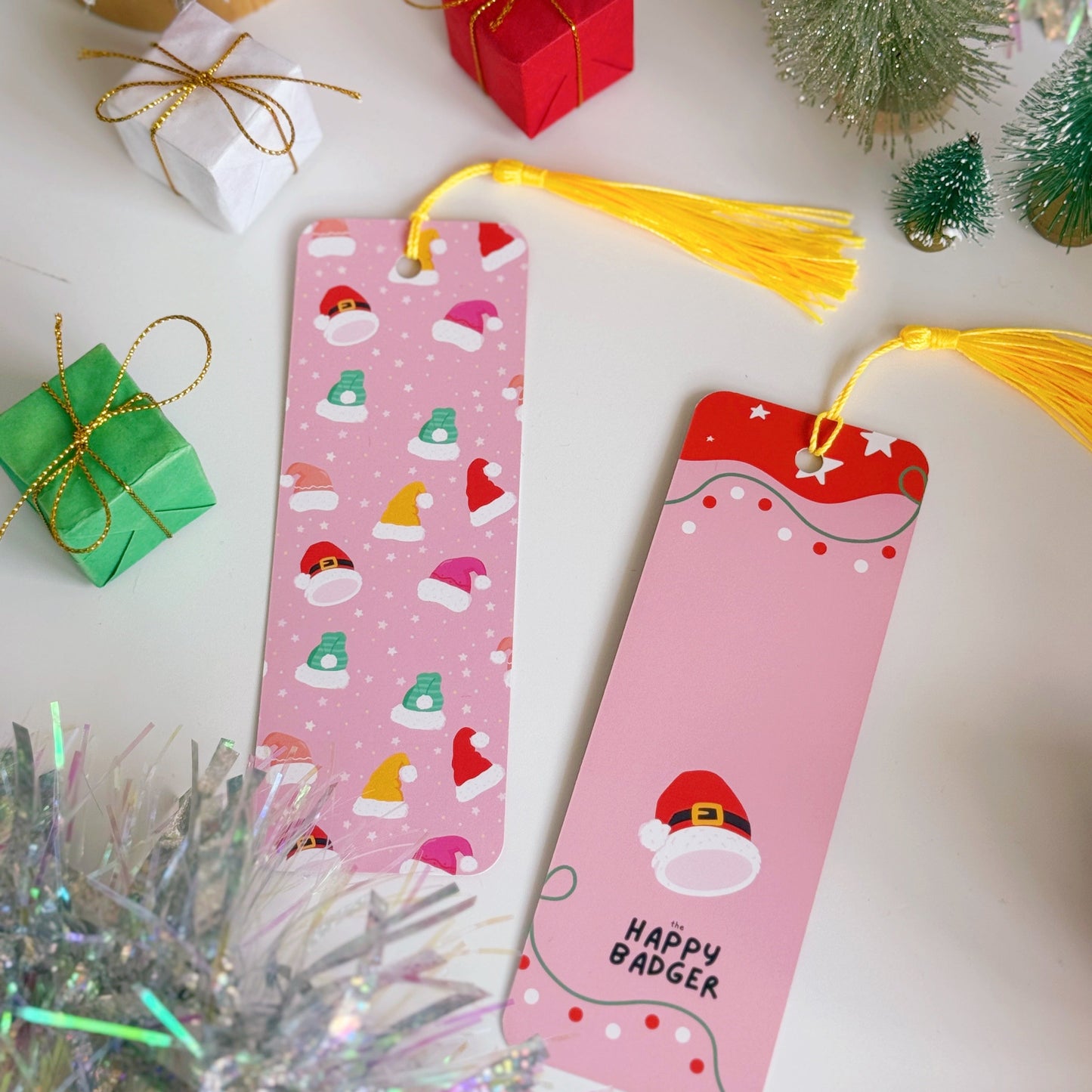 Two Christmas-themed bookmarks with tassels on a festive background with decorations.