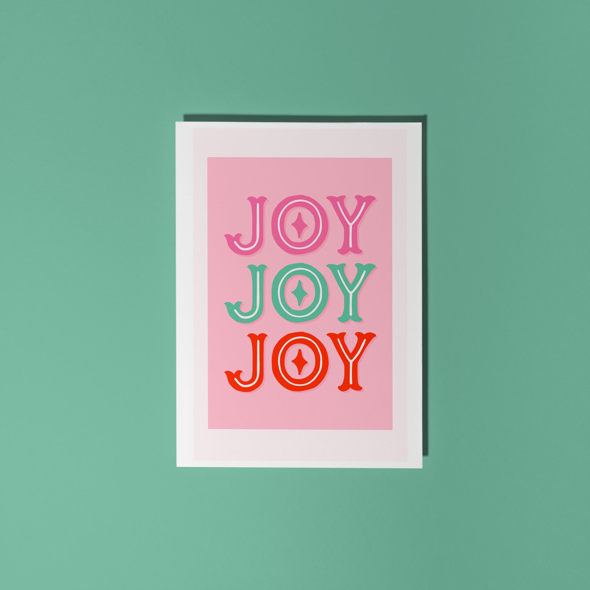 Christmas card with 'JOY' text in different colours on a pink background
