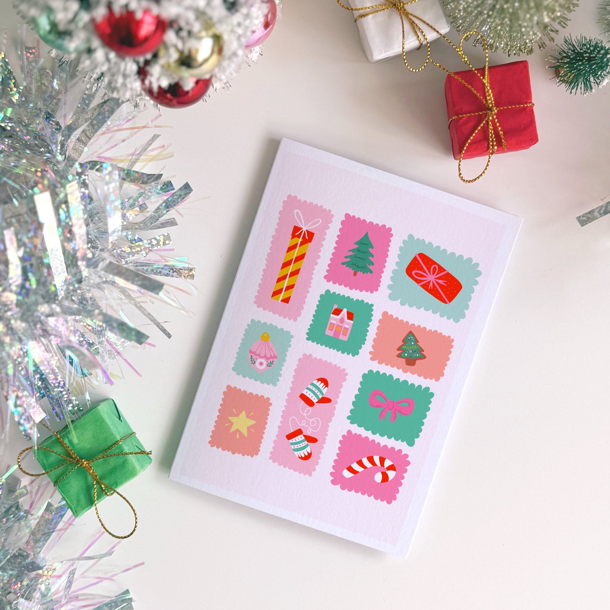 Christmas card with festive designs surrounded by tinsel and small gift boxes.