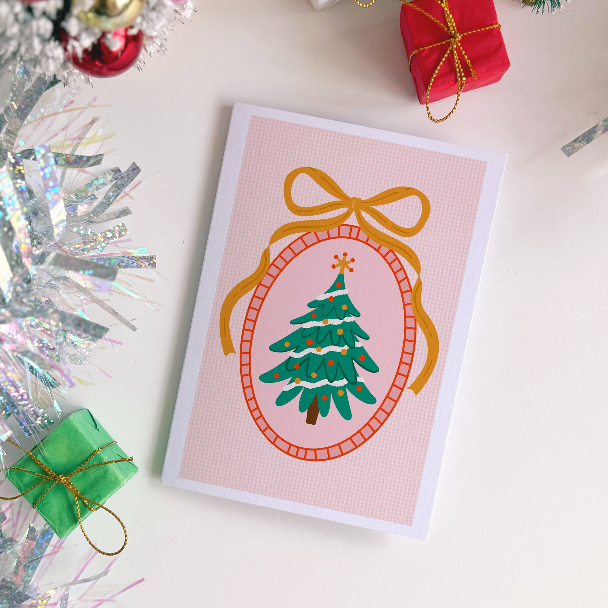 Christmas card with a tree design surrounded by festive decorations on a white surface.