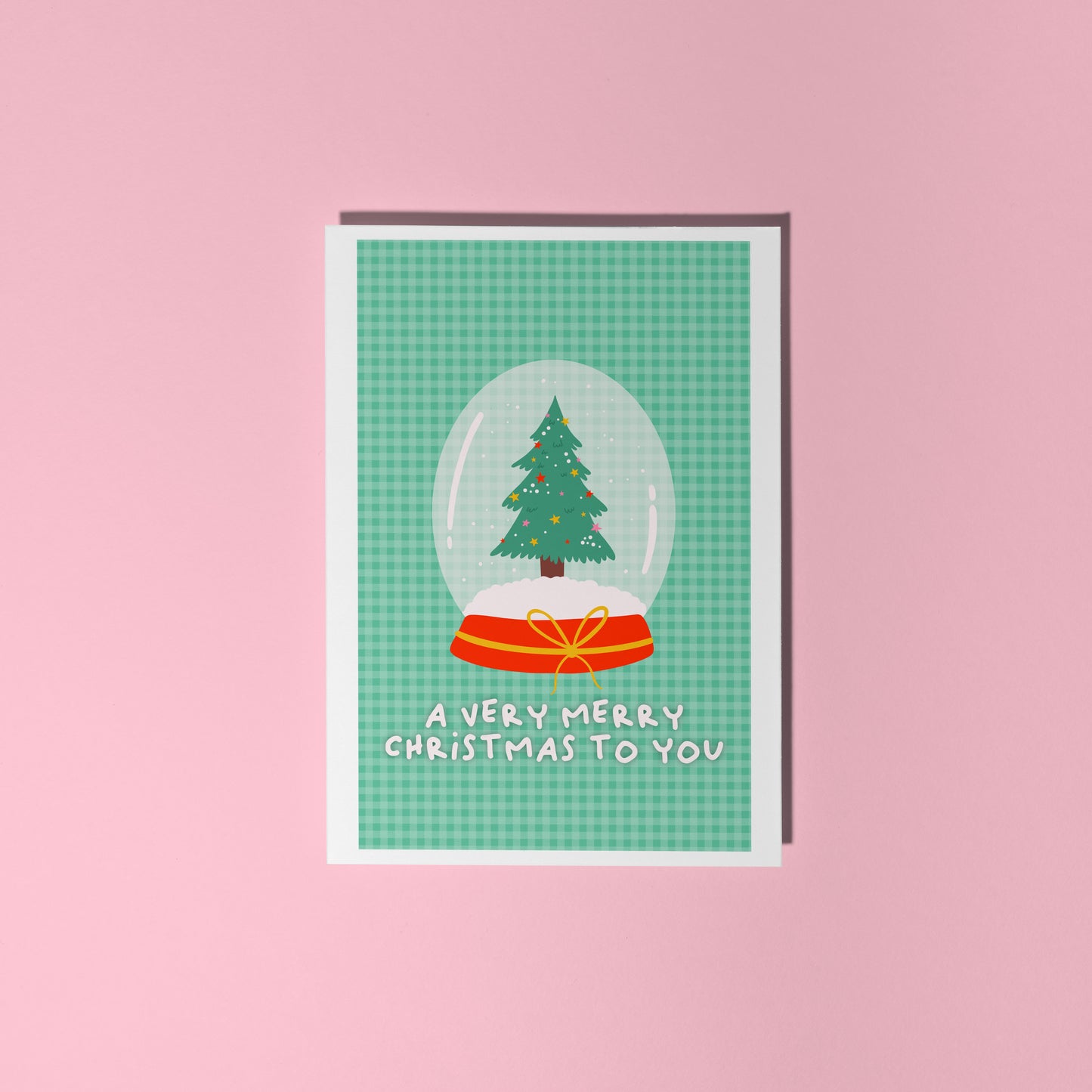 Christmas card with a snow globe design featuring a tree on a pink background