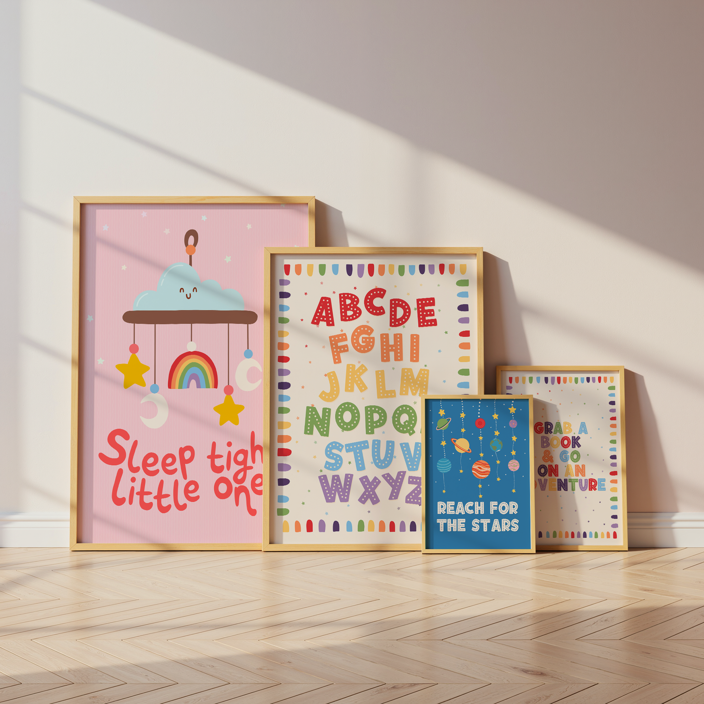 Four framed children's wall art prints leaning against a wall on a light wood floor. The largest print on the left says 'Sleep tight little one' with a pastel cloud and rainbow illustration.