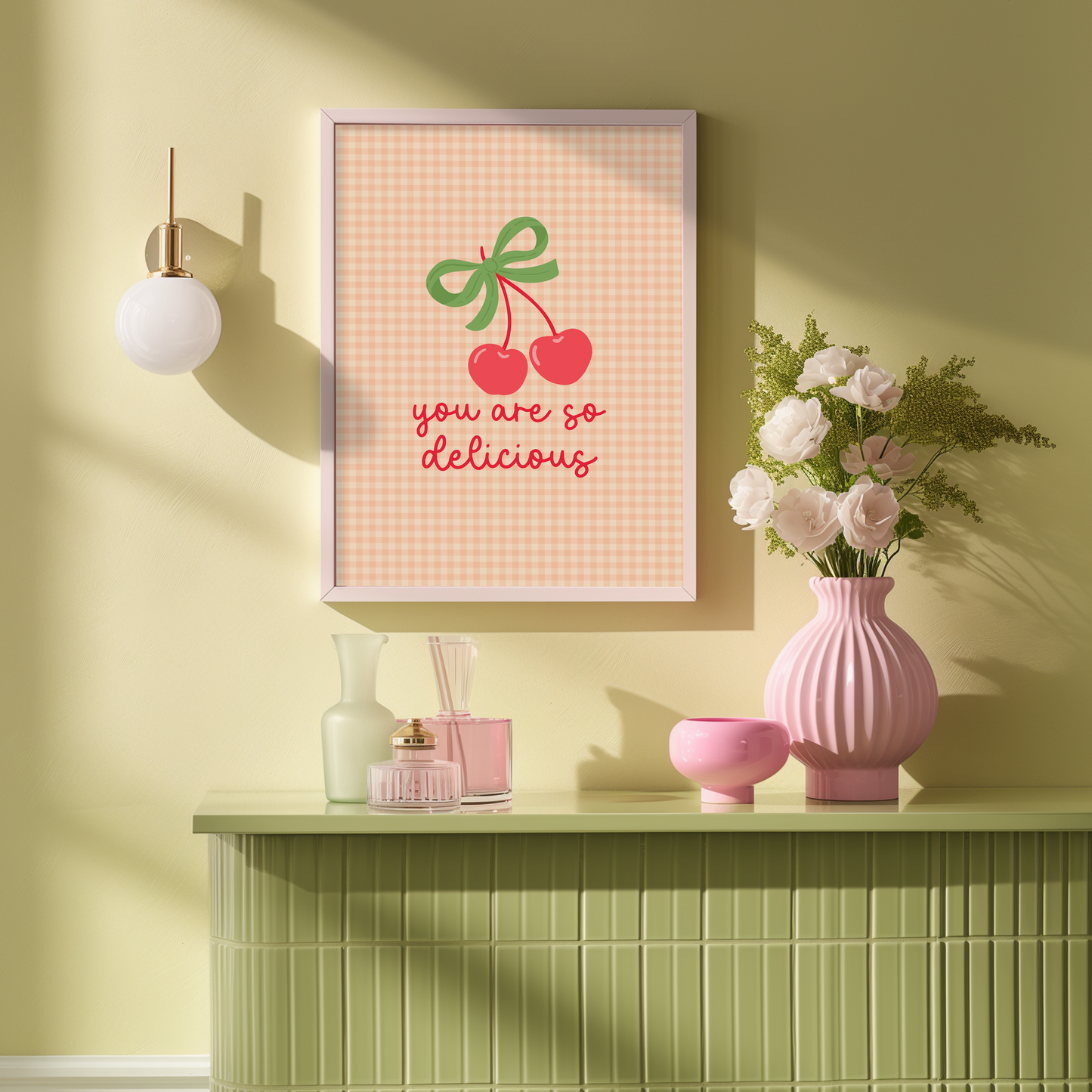 An orange gingham background print, with an illustration of red cherries tied together with a green bow, and the quote saying 'you are so delicious' below.
