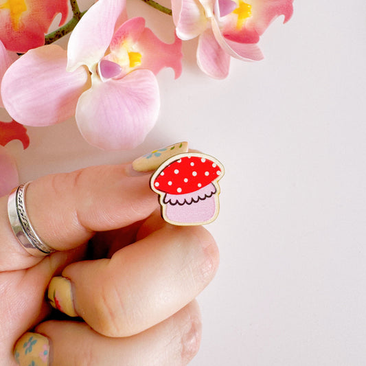 A tiny mushroom pin badge in red and pink.