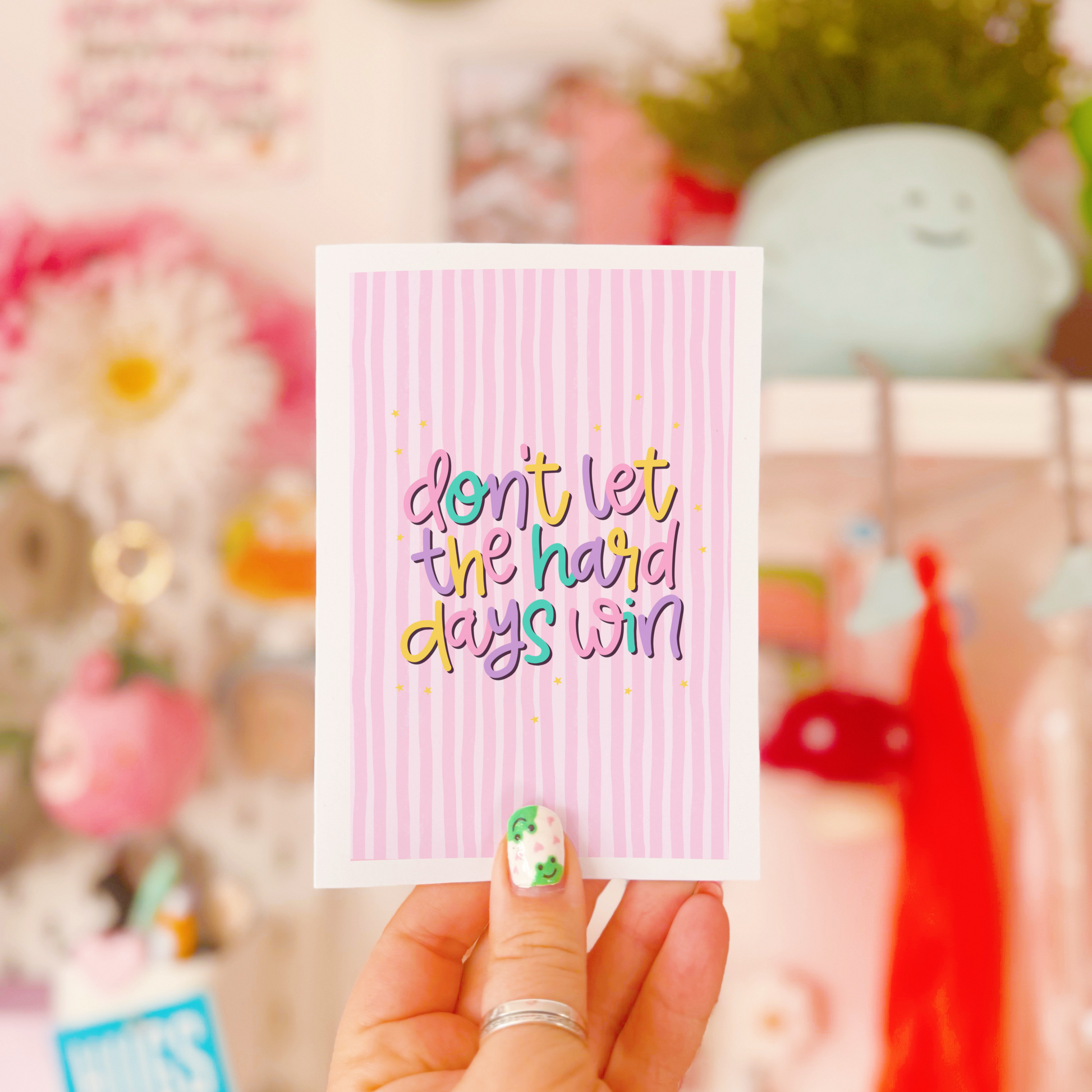 a greeting card, with a pink striped background, and colourful text reading 'Don't let the hard days win'