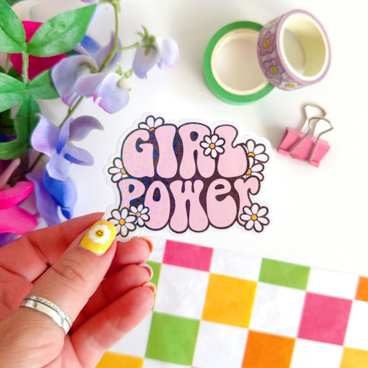 A holographic sticker with the words 'GIRL POWER' in bold pink lettering, with little white daisies surrounding the text.