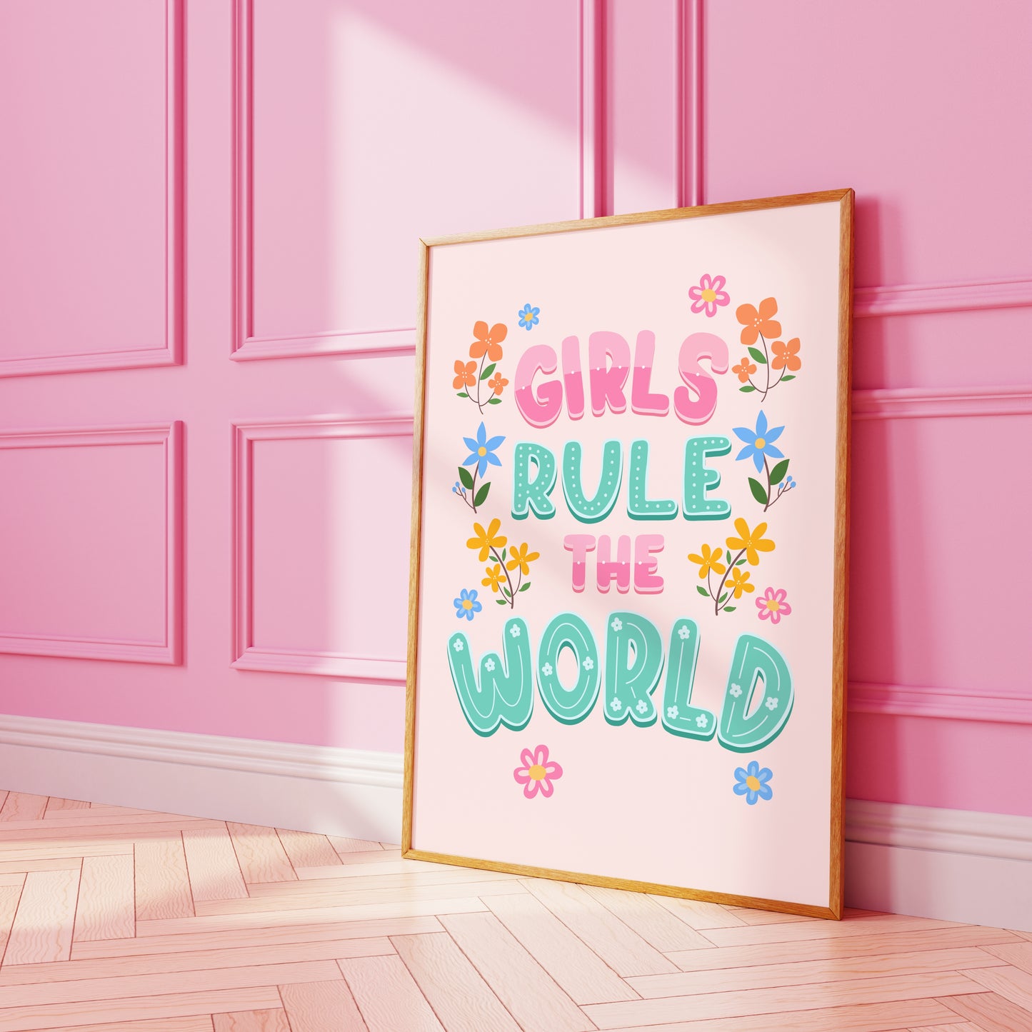 A bright vibrant print saying 'Girls Rule The World' in pink and teal, with flowers illustrated around the sides.