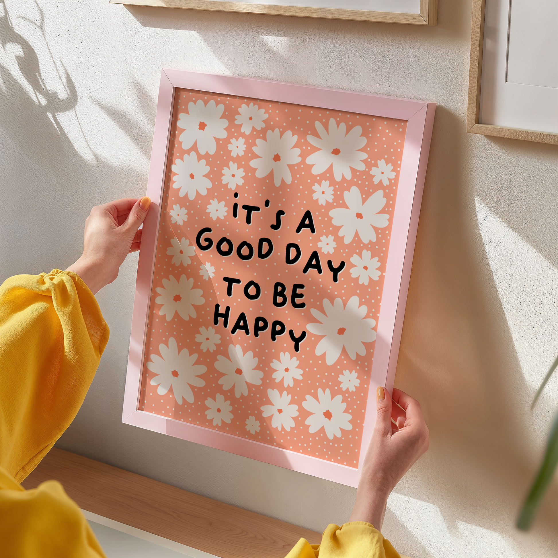 Several off-white daisies, and the words 'it's a good day to be happy' in black, all on a soft orange background print.