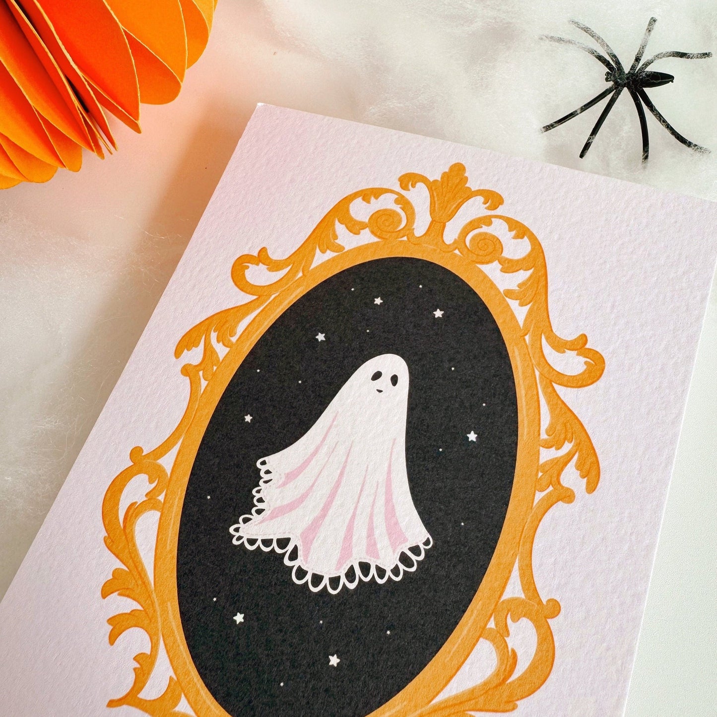 A halloween themed postcard of a ghost in a golden ornate frame.