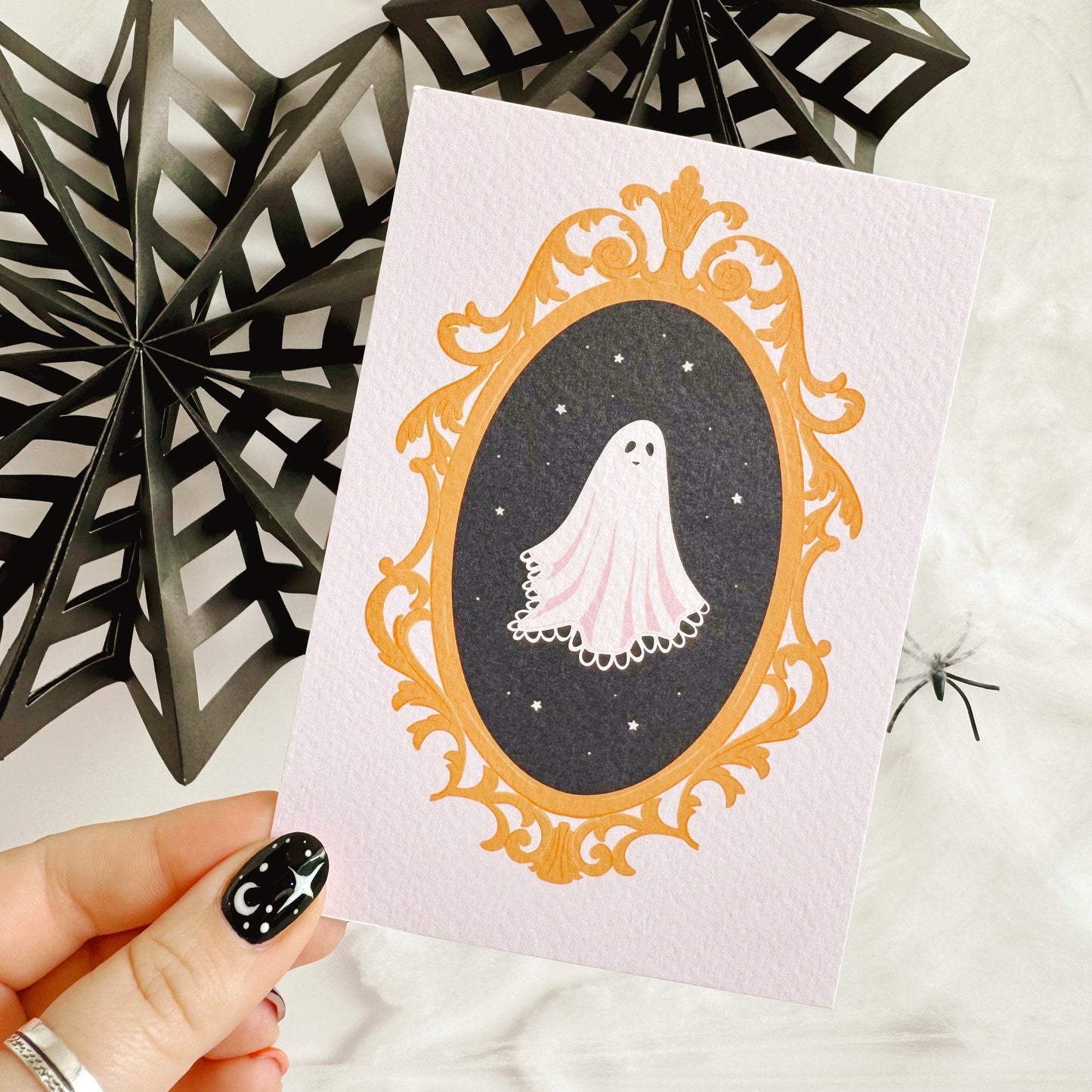 A halloween themed postcard of a ghost in a golden ornate frame.