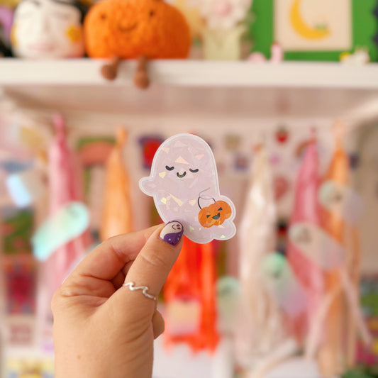 Hand holding a cute ghost sticker with a blurred colorful background