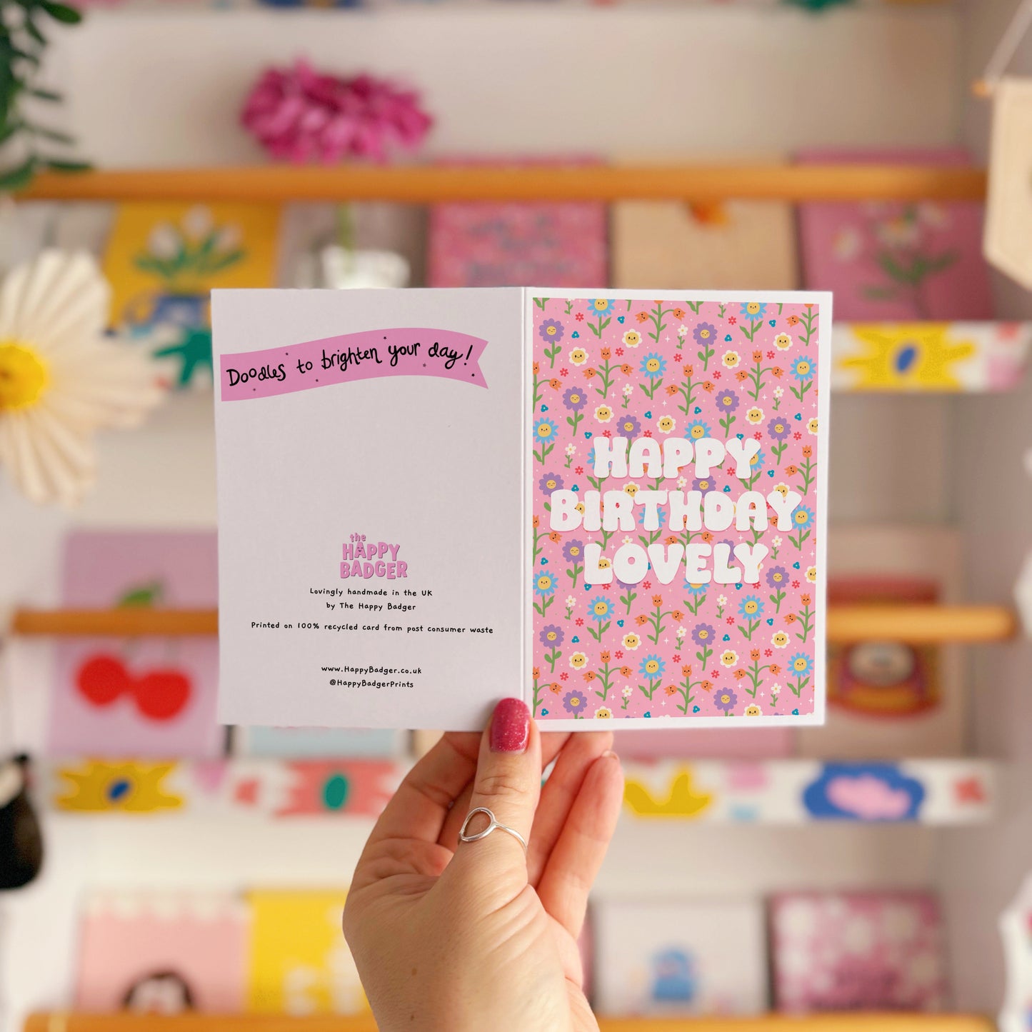 A pink floral birthday card, with white text that reads 'Happy Birthday Lovely'.