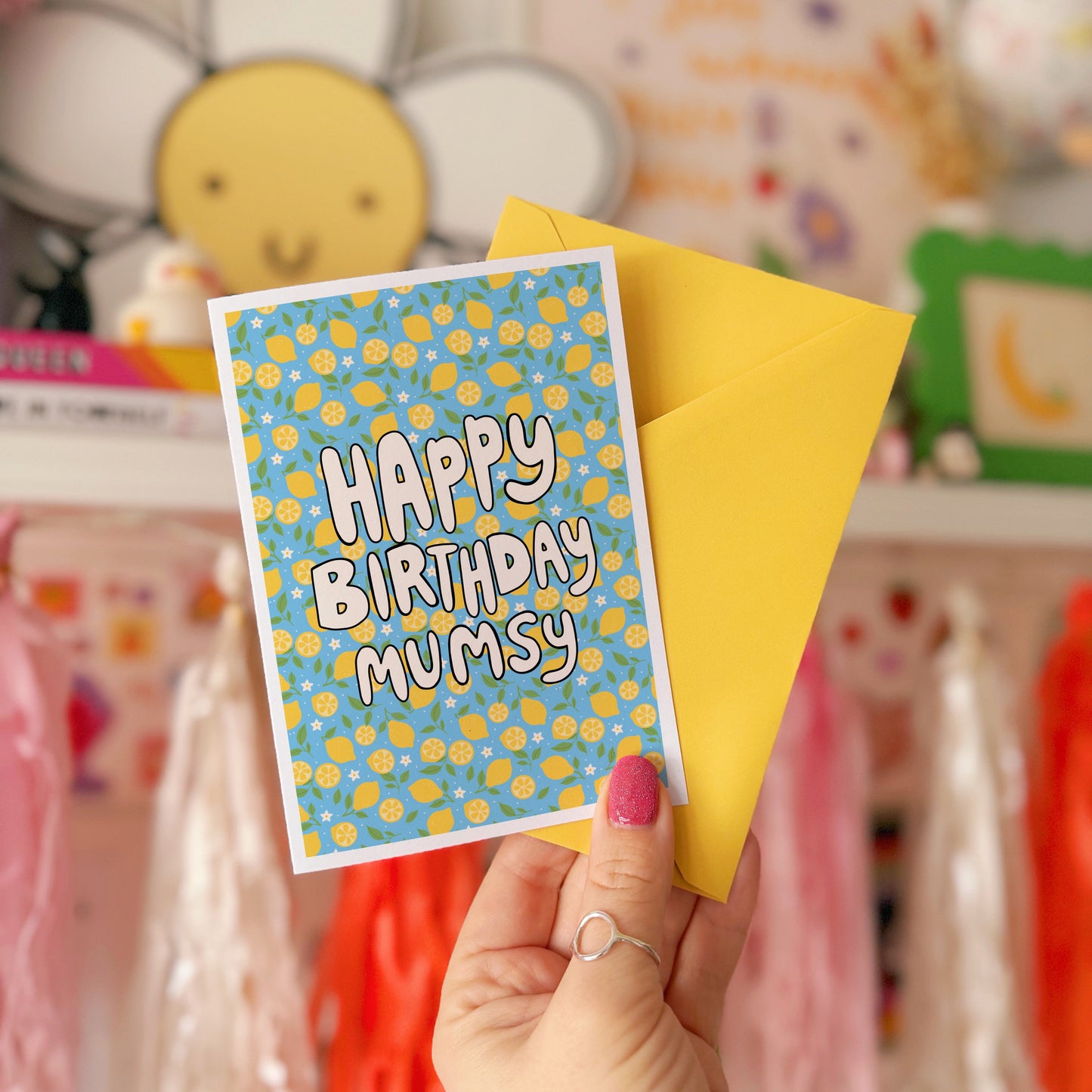 A blue card with a lemon pattern, and white chunky text that reads 'Happy Birthday Mumsy' in the centre.