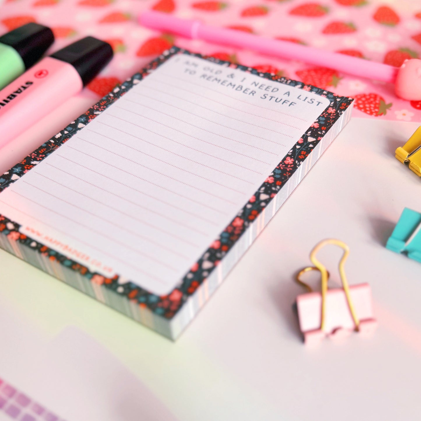 A lined notepad with a black floral pattern on the edges and a quote at the top that reads 'I am old and I need a list to remember stuff'.