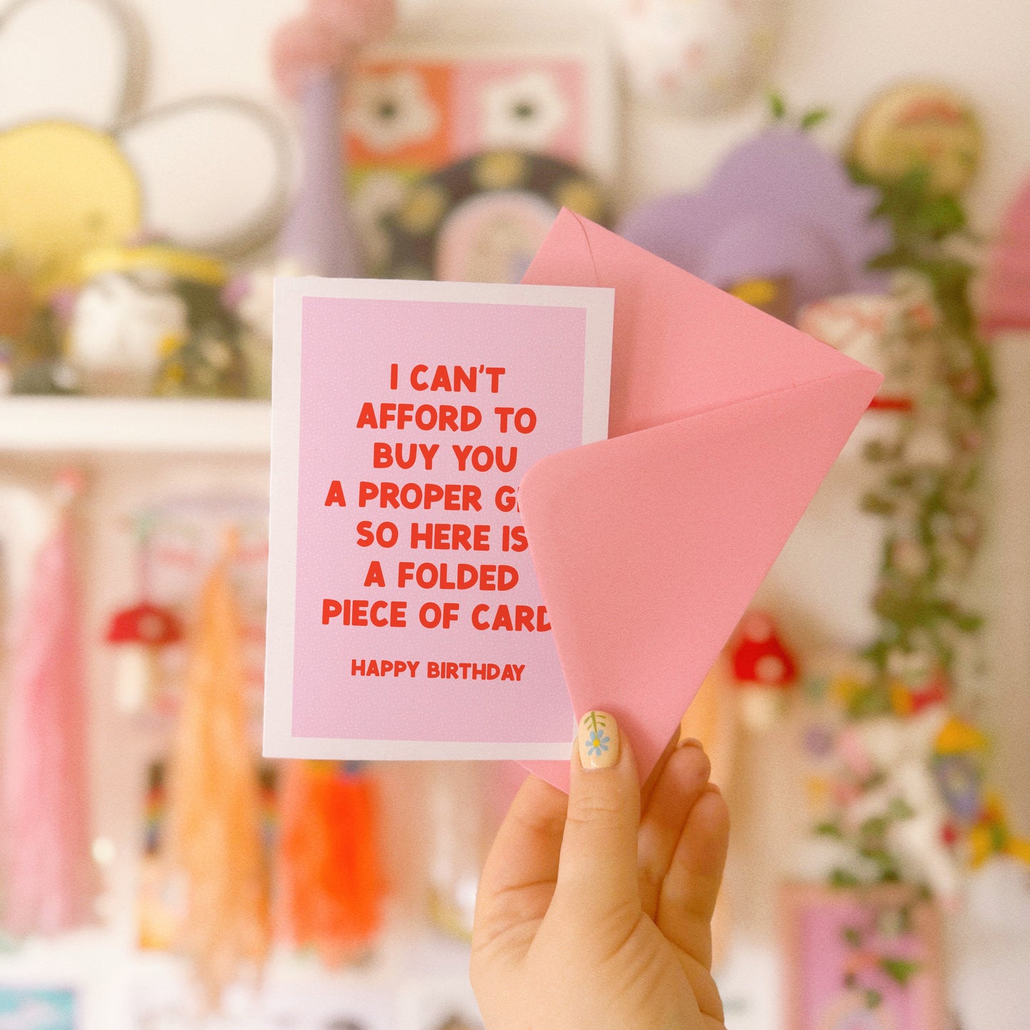 A pink card with red text, saying I can't afford to buy you a proper gift so here is a folded piece of card - happy birthday.