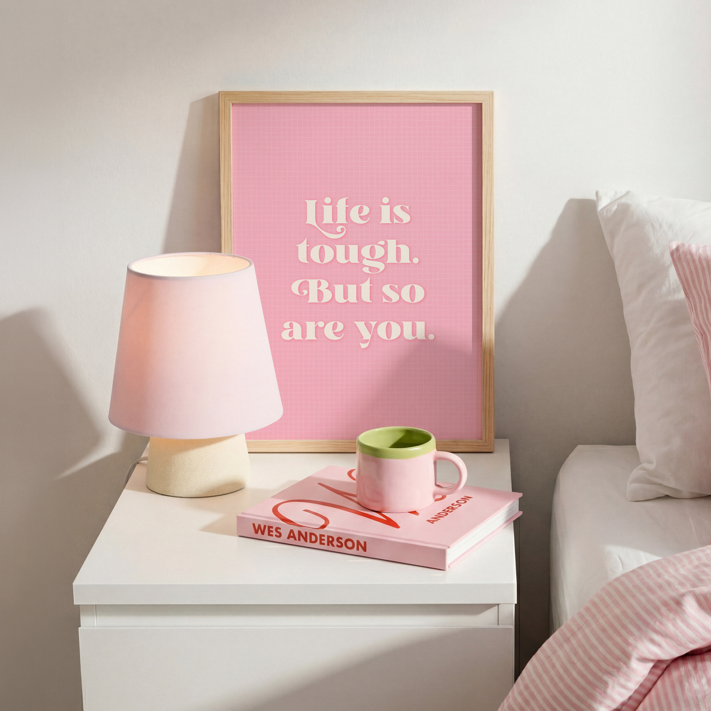A pink print with a soft check pattern, and a quote in white that reads 'life is tough. But so are you.'.