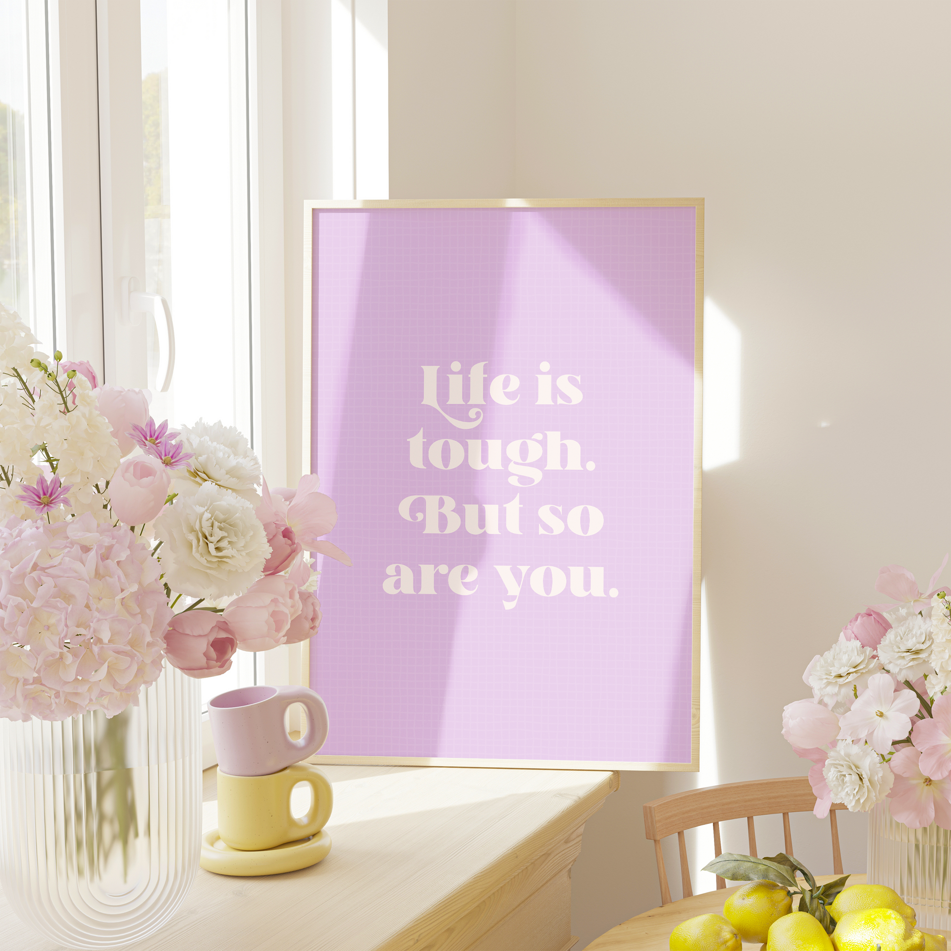 A framed print with a purple background and blue frame, containing the text 'Life is tough. But so are you.' in white font.