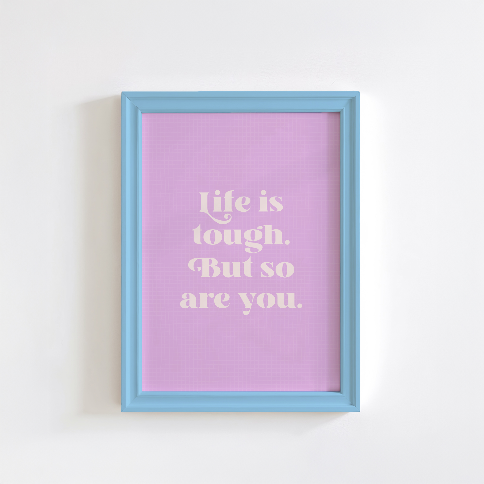 A framed print with a purple background and blue frame, containing the text 'Life is tough. But so are you.' in white font.