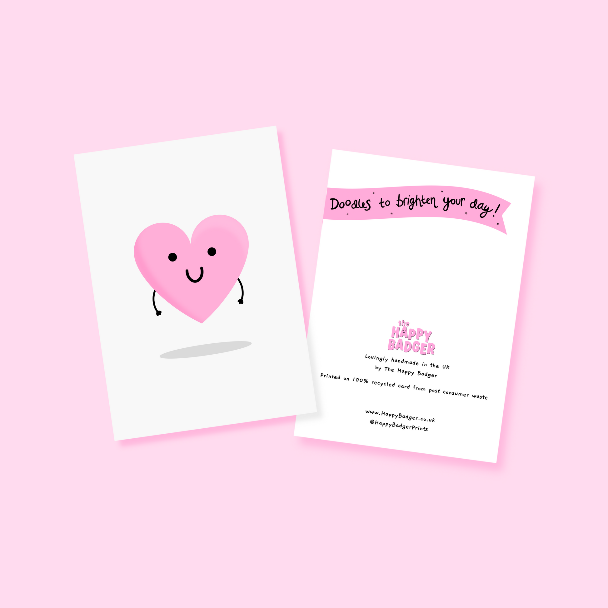 A pink love heart with arms and a smiling face, on a greetings card.
