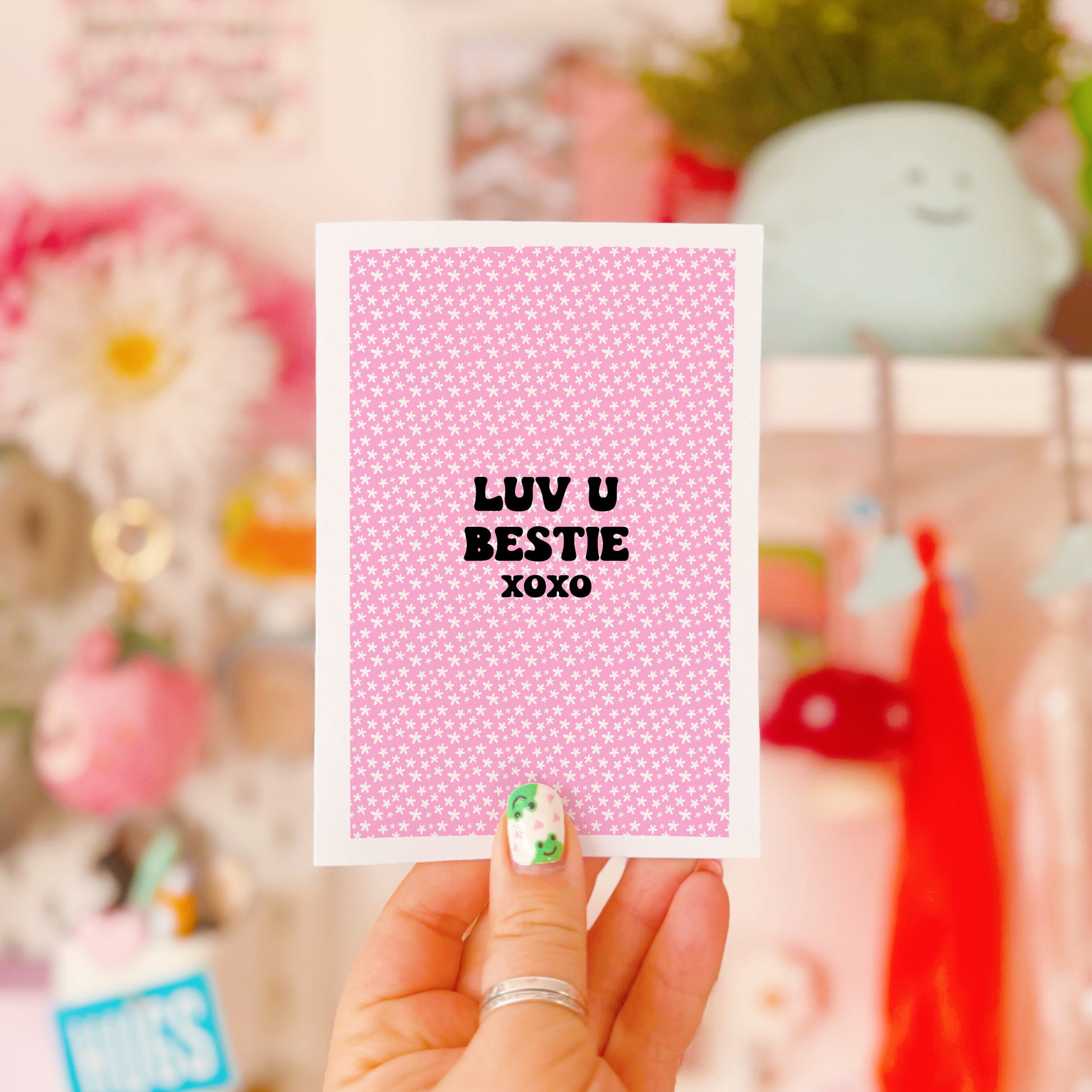 A pink greetings card, with the message 'Luv u bestie xoxo' on the front.