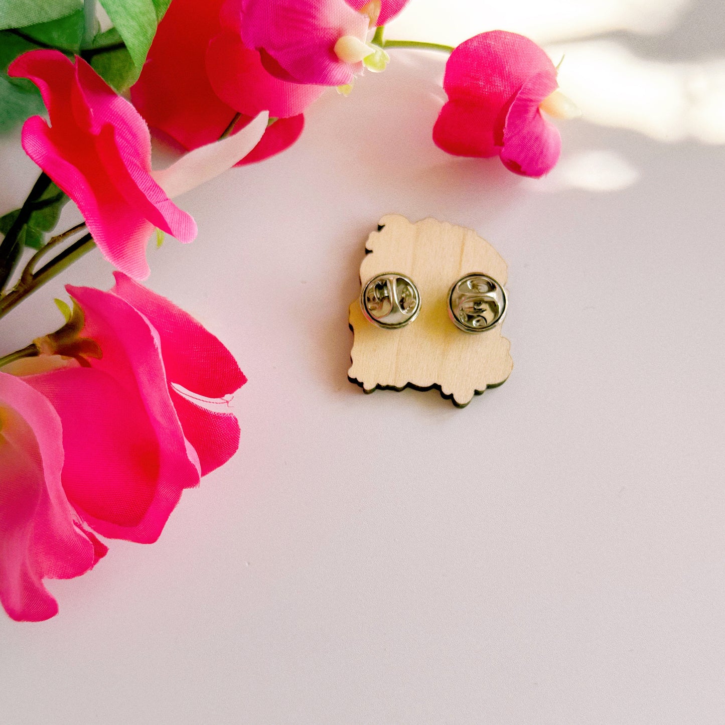 The back of a pin badge with two metal clasp fastenings