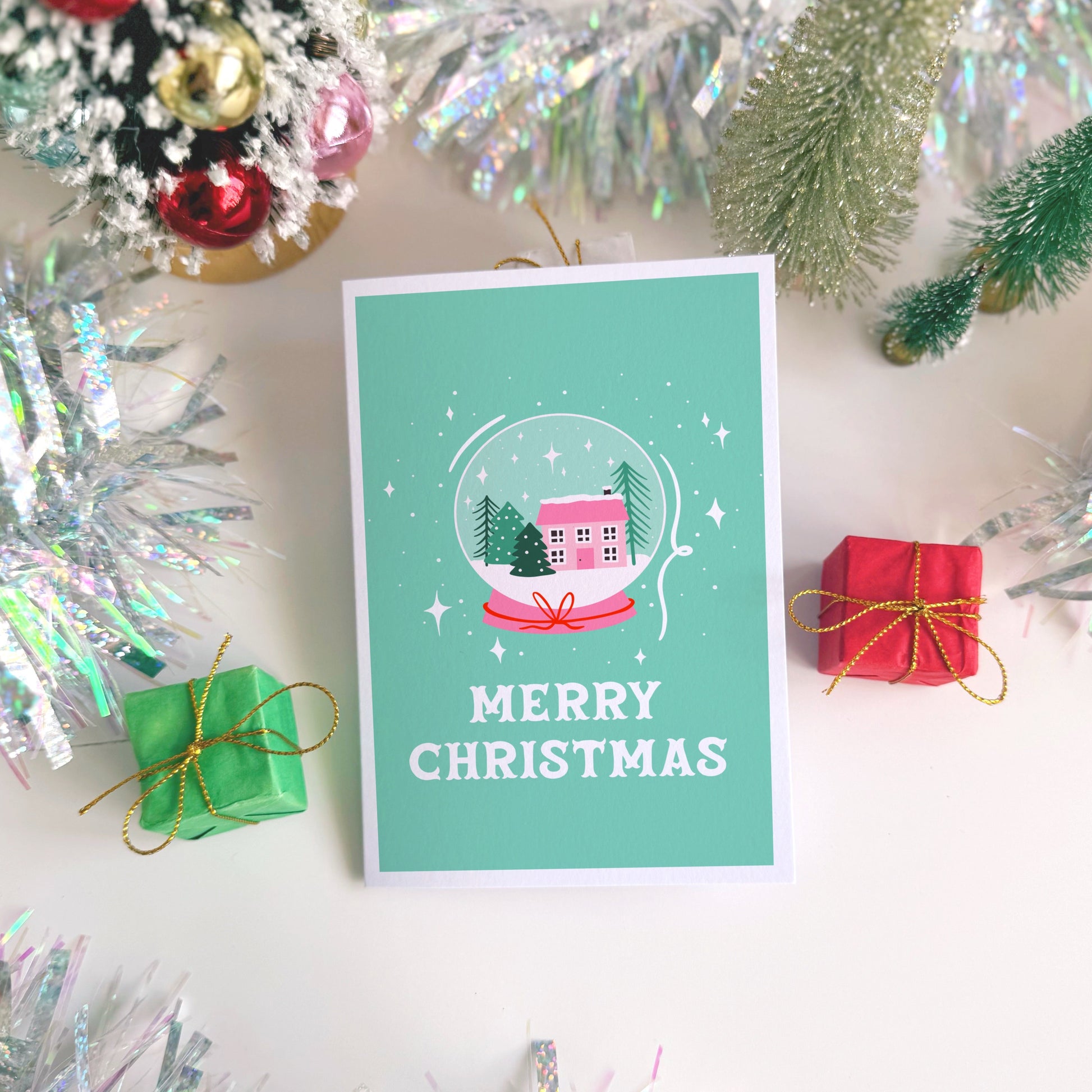 Christmas card with a snowy scene and 'Merry Christmas' text, surrounded by festive decorations.