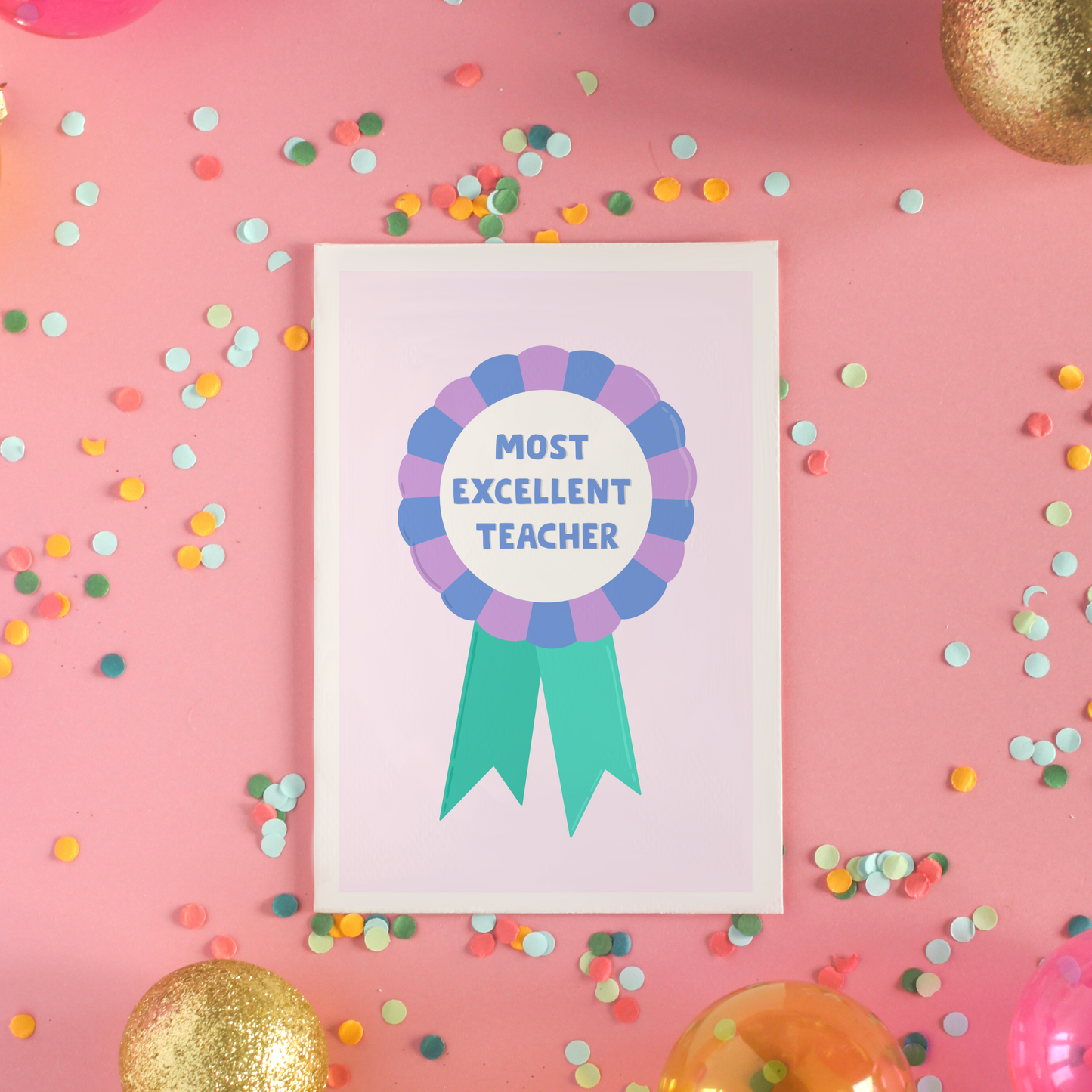 A greetings card with a rosette with text saying most excellent teacher. The colour combo is green blue and purple.