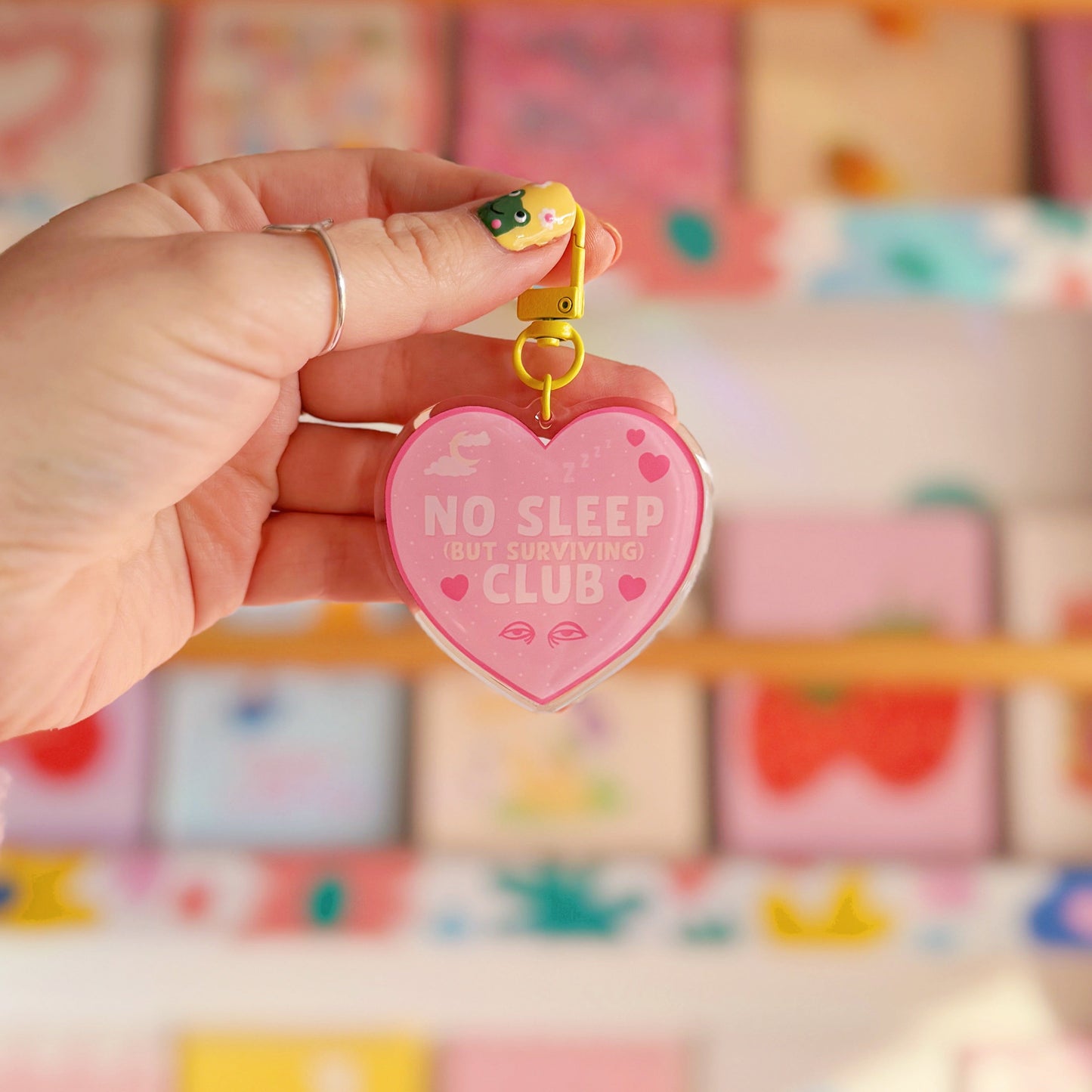 Heart-shaped keychain with 'No Sleep But Surviving Club' on, with a yellow clasp.