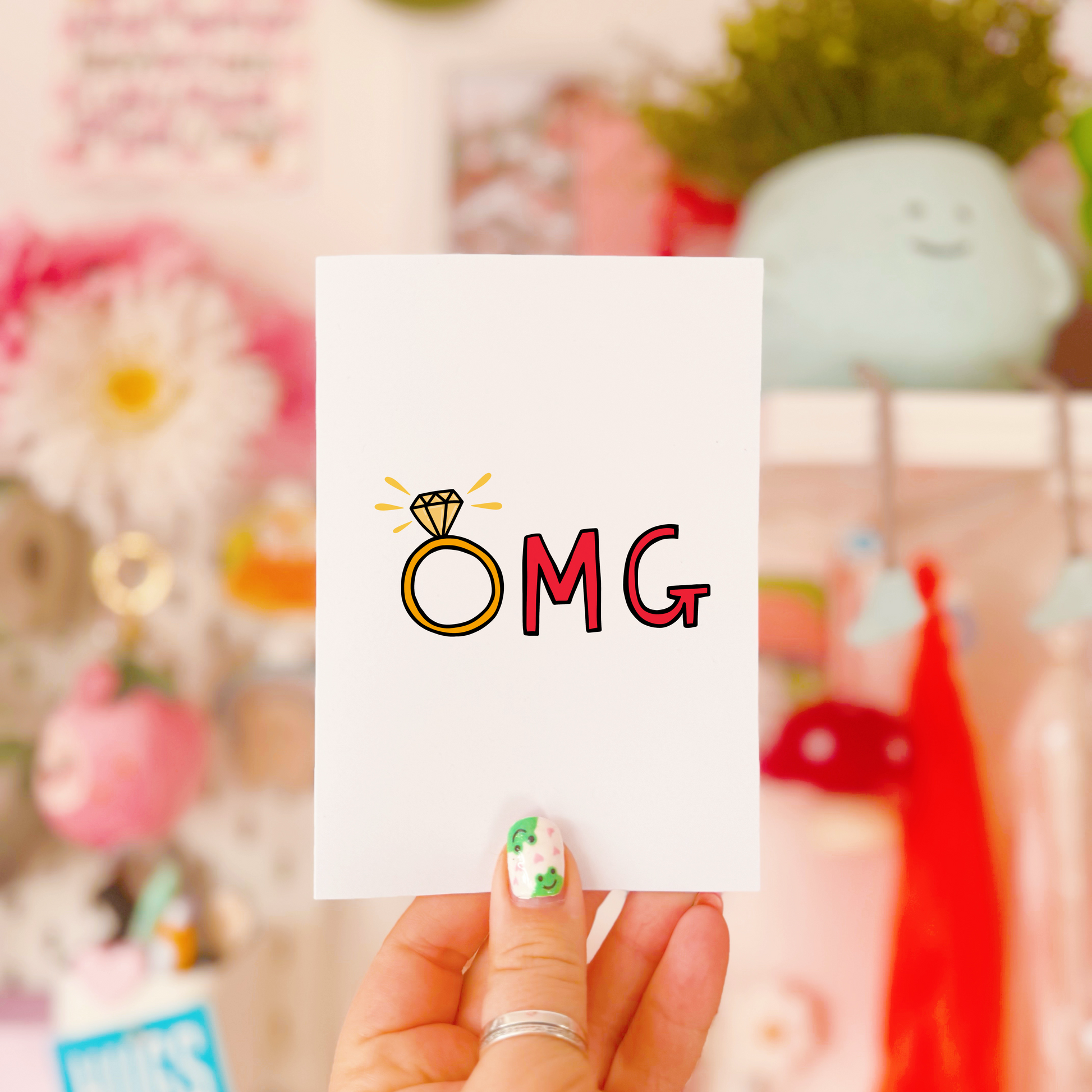 A greetings card that says OMG in hand drawn lettering, with the O as an engagement ring.