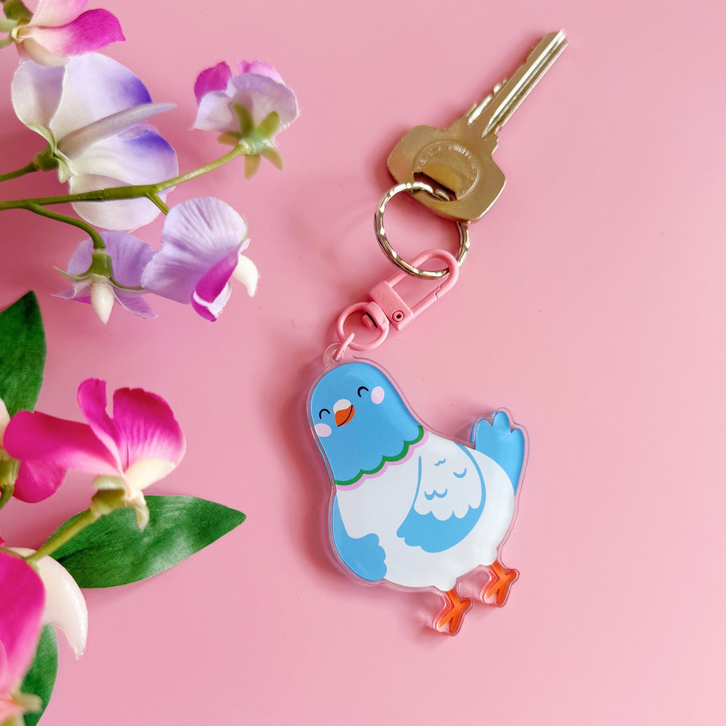 Keychain with a blue bird design on a pink background with flowers