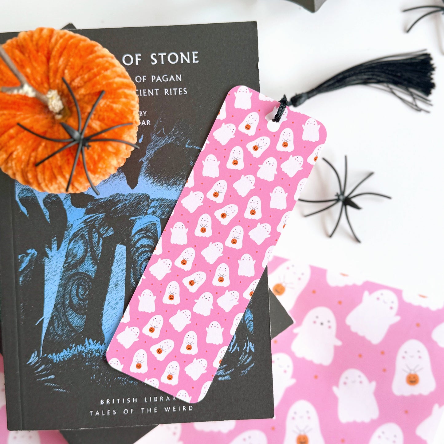 A pink bookmark with little cute ghosts all over it, and a coordinating black tassel.