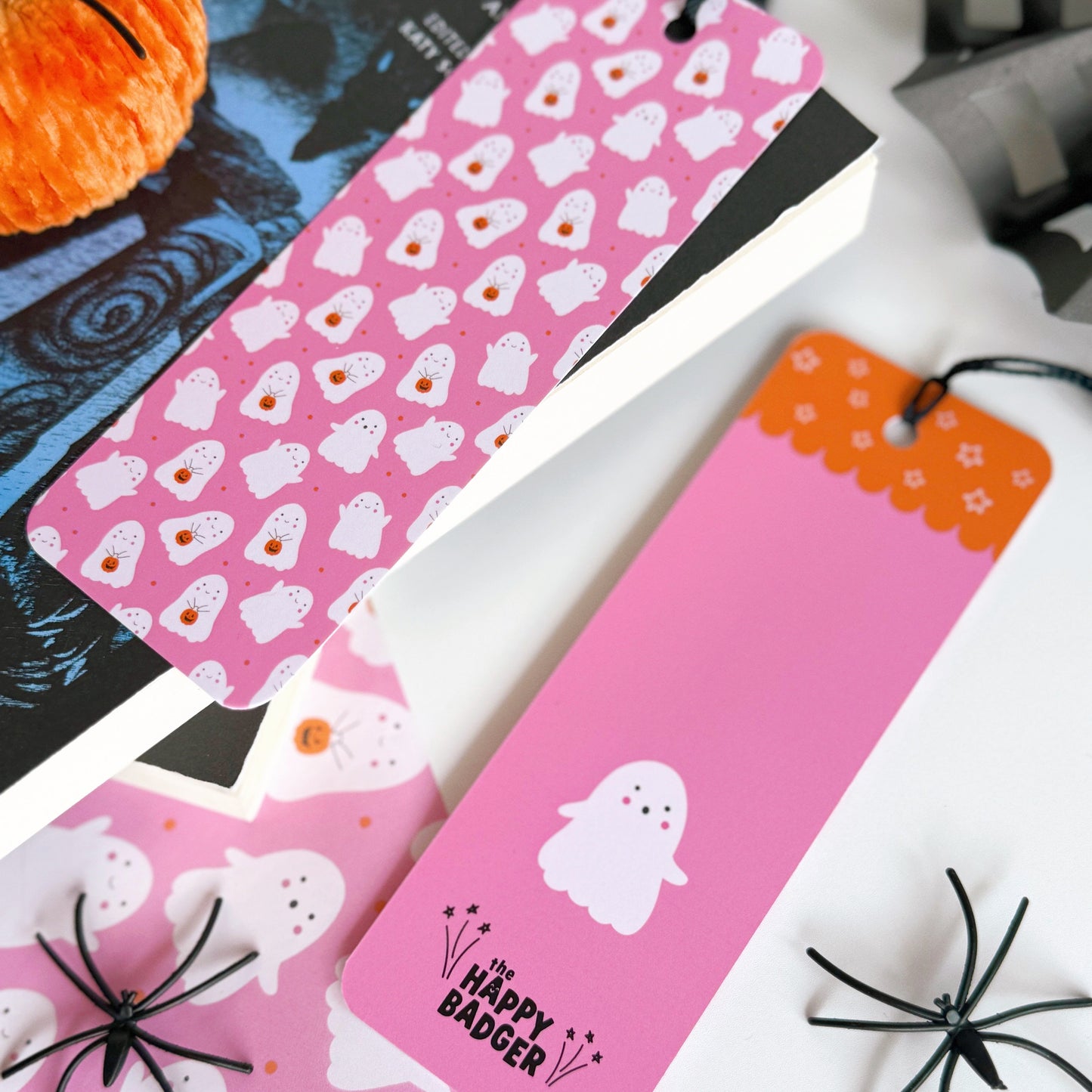 A pink bookmark with little cute ghosts all over it, and a coordinating black tassel.