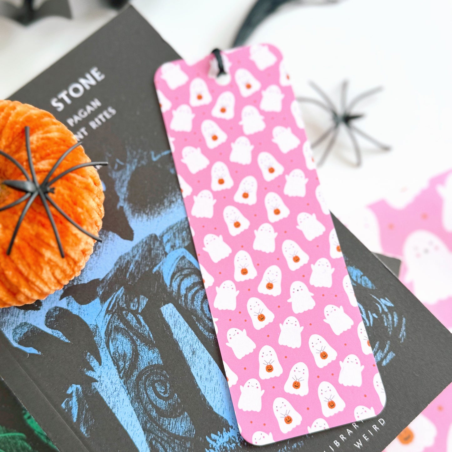 A pink bookmark with little cute ghosts all over it, and a coordinating black tassel.