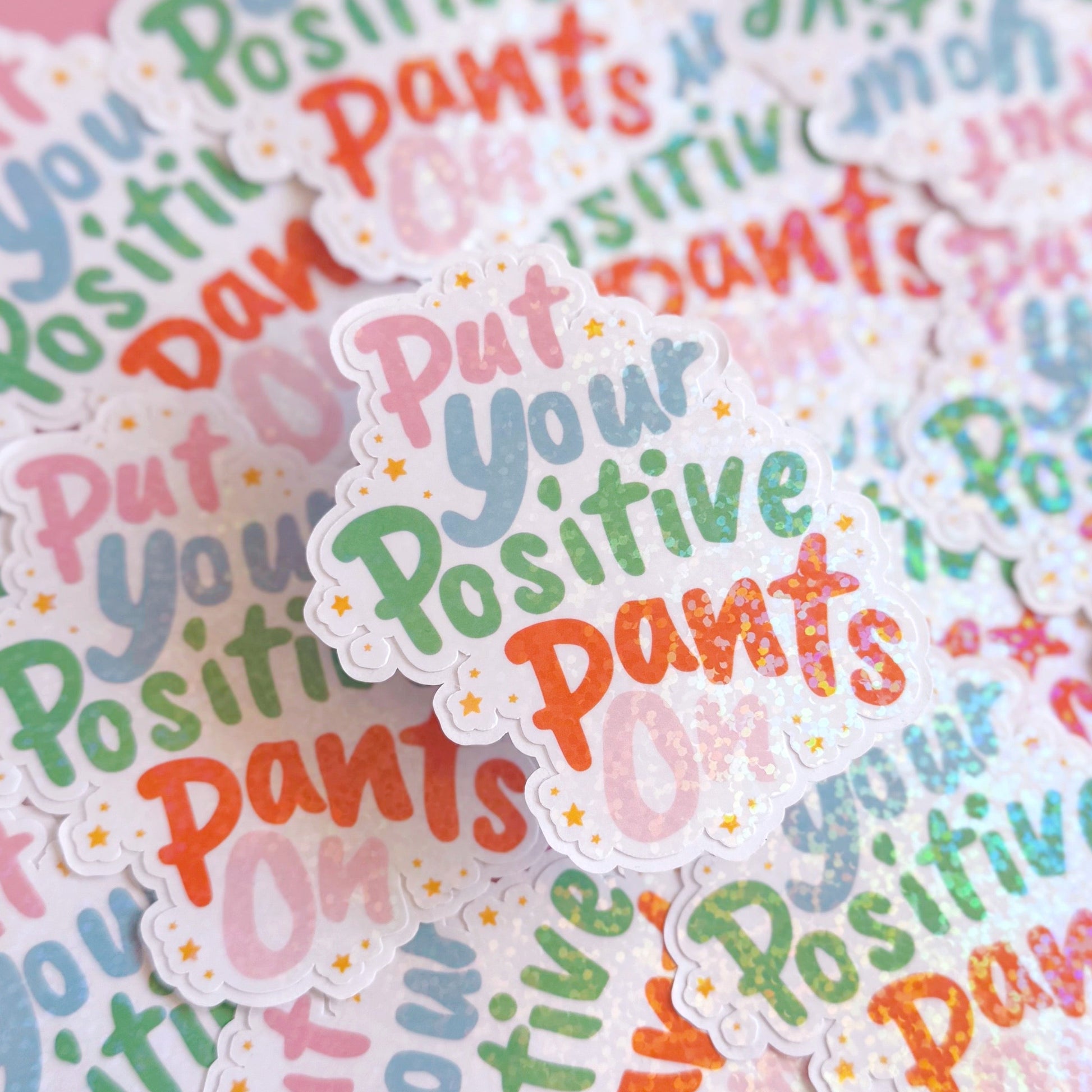 A colourful sticker with the quote 'put your positive pants on' on.