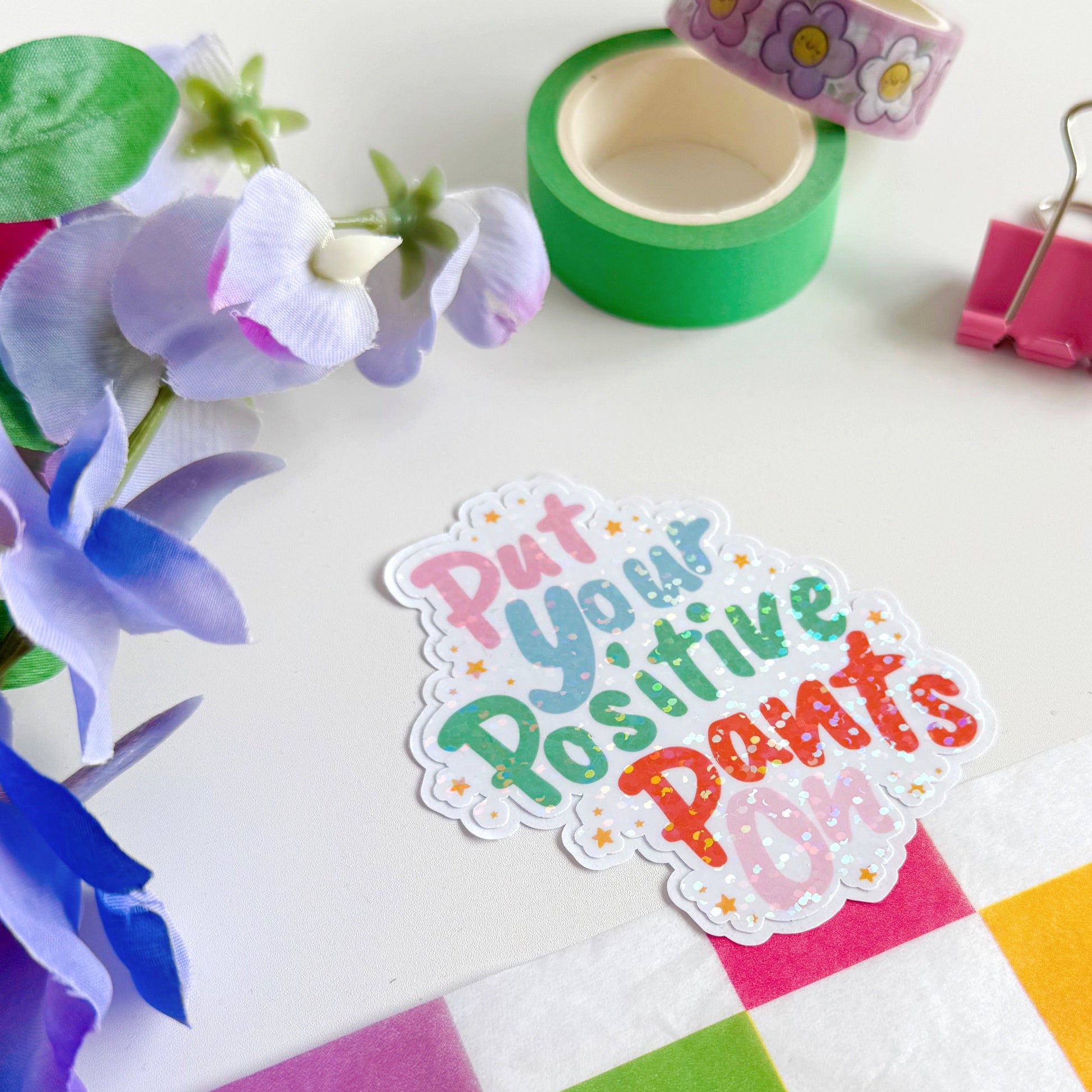 A colourful sticker with the quote 'put your positive pants on' on.