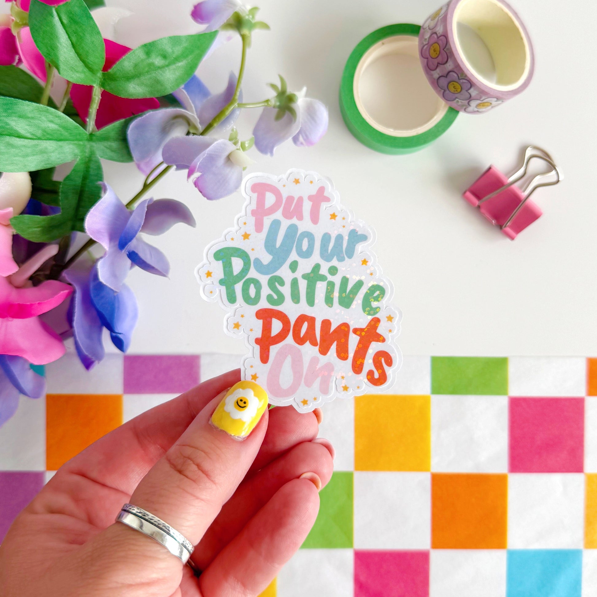 A colourful sticker with the quote 'put your positive pants on' on.