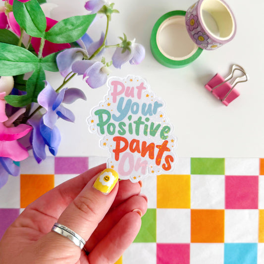 A colourful sticker with the quote 'put your positive pants on' on.