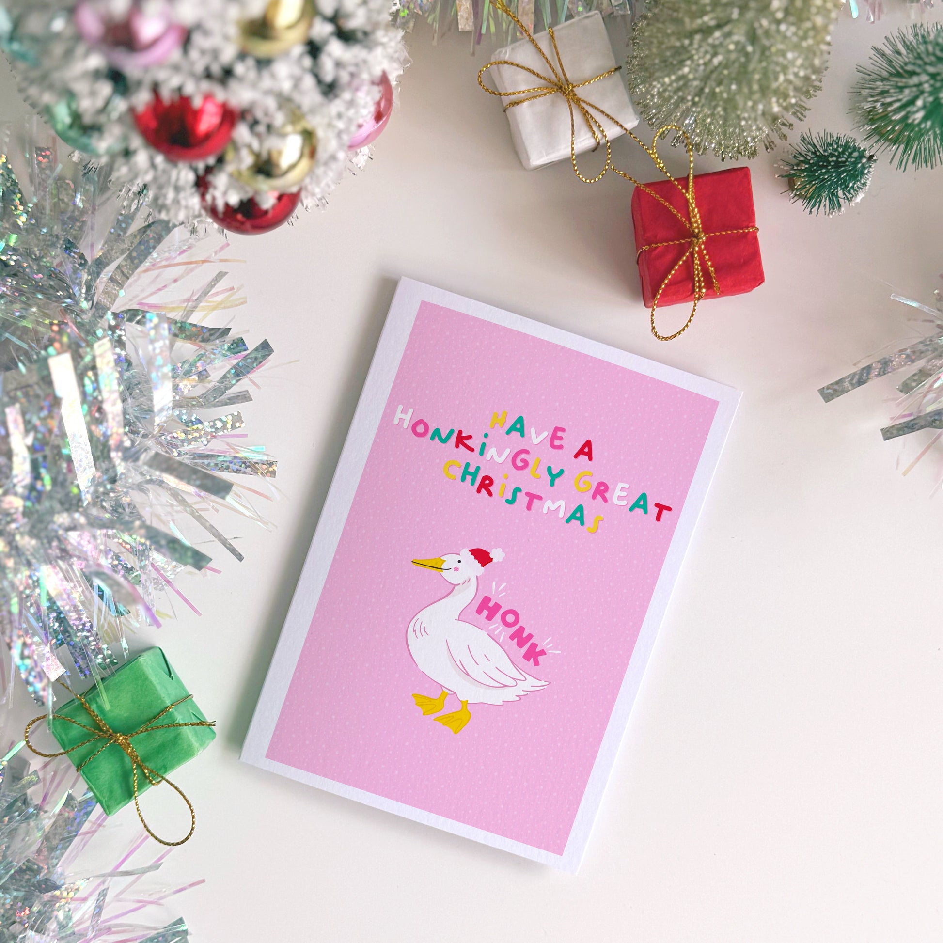 Pink Christmas card with a goose illustration and text that reads 'have a honkingly great christmas' above.
