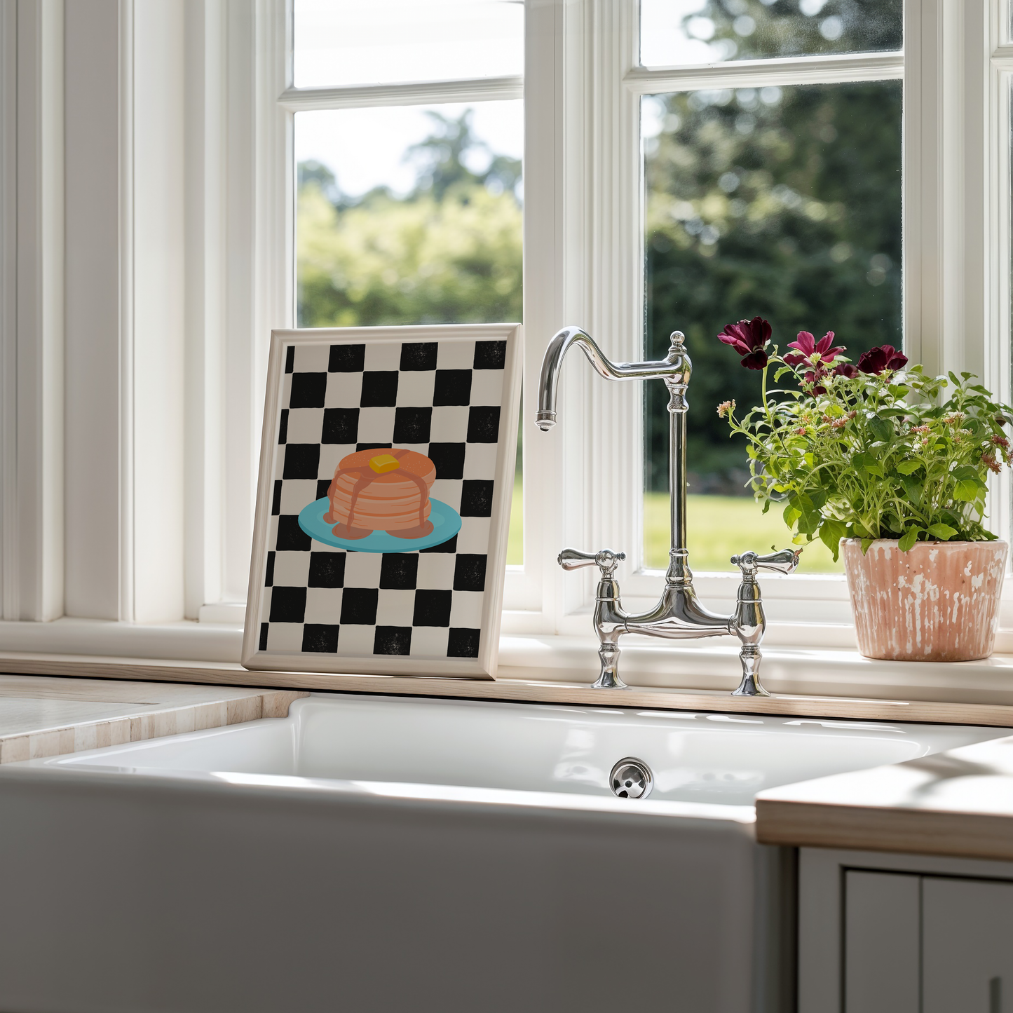 A framed art print featuring a black and white checkered pattern with a colourful illustration of pancakes on a blue plate.