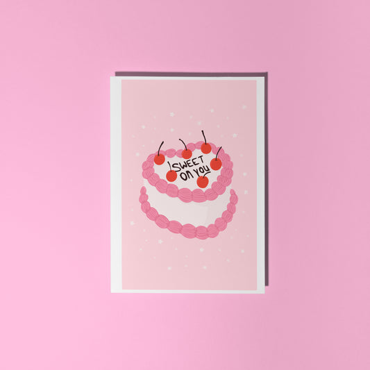 A pink greetings card with an illustration of a cake with pink and white icing, that says 'sweet on you' on the top of the cake.
